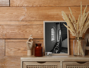 Black and white interior showing dark timber stairs against pale walls and window light.
