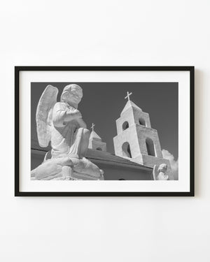 Angel statue and cross-topped church towers in Clarence Town, Bahamas, photographed in black and white.