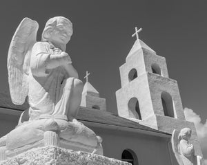 Pale angel figure in front of church towers against a dark sky in the Bahamas.