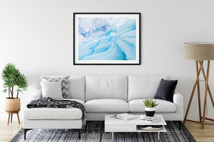 Natural blue and white iceberg forms with sweeping clouds above Antarctica.
