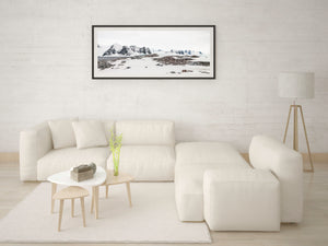 Distant mountains rise above snow-covered terrain and a gentoo penguin nesting area.