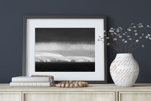 Rough ice faces catch pale light along an Antarctic coast beneath heavy cloud.