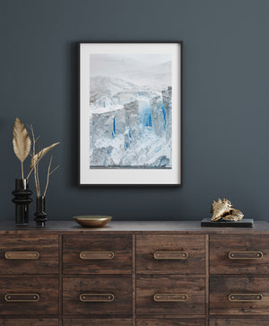 A snowy Antarctic slope rises behind rugged ice cliffs and a thin waterline.