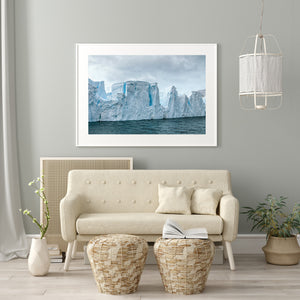 Rough ice patches line the water beneath pale Antarctic cliffs and blue recesses.