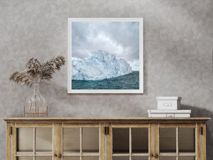 Pale Antarctic ice with fractured ridges and blue recesses above dark ocean water.