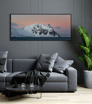 A pale Antarctic mountain beneath warm dusk clouds and a cool grey horizon.