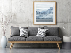 Jagged dark peaks meet smooth snow slopes along an Antarctic coast.