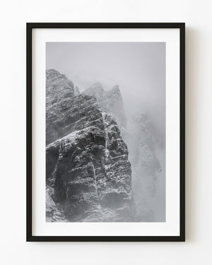 Rugged Antarctic mountain rising through blowing snow.