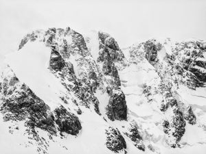 Jagged Antarctic mountain walls and broad snowfields in monochrome.