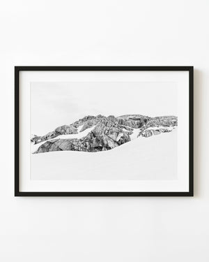Exposed Antarctic rock ridge above pale snow in black and white.