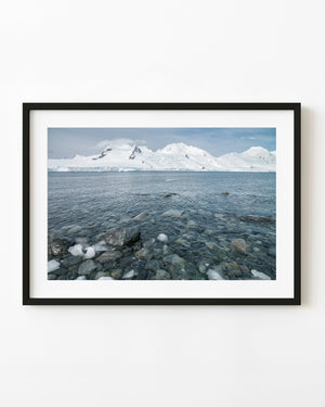Clear Antarctic coastal water beneath distant snowy mountains.