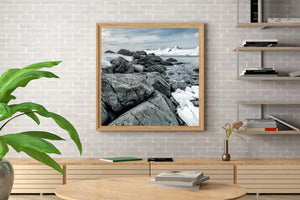 Large coastal boulders beneath a pale, clouded Antarctic sky.