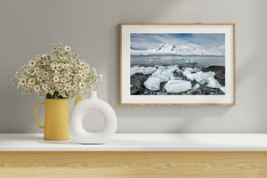Translucent ice fragments among dark stones on an Antarctic coast.
