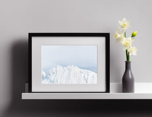 A pale Antarctic mountain ridge with layered snow and soft blue shadows.