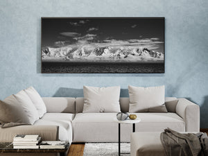Black and white Antarctic seascape with snow peaks and rippled ocean.