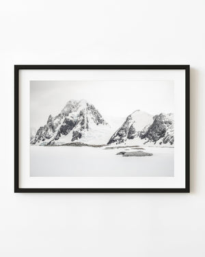 Dark Antarctic mountain peaks above an open white snowfield.