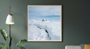 Dark rock on a snowy Antarctic mountain beyond a broad white foreground.