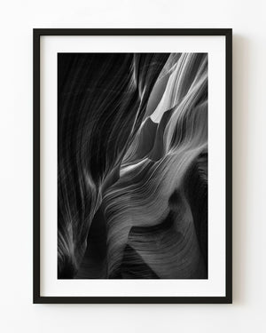 Flowing Antelope Canyon sandstone around a bright opening in black and white.