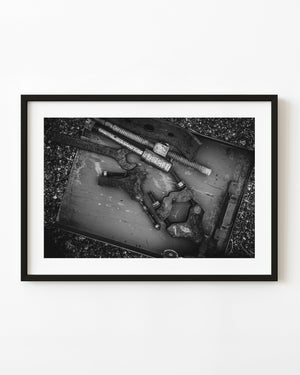 Antique industrial tools and threaded rods in a metal tray, photographed in black and white.
