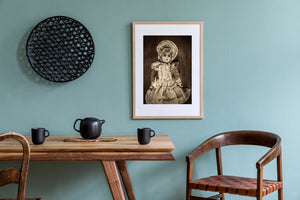 Lace ribbons and a pleated bonnet frame the face of an antique porcelain doll.