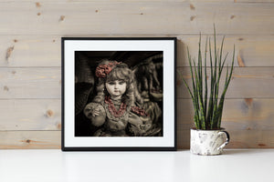 Close portrait of an antique porcelain doll with curls and muted red lace trim.