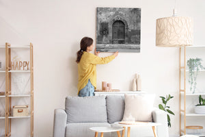 Black and white view of an arched Italian door surrounded by weathered plaster.