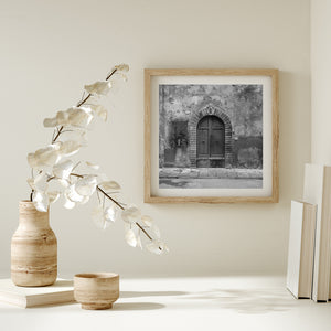 Old Tuscan doorway with stone blocks, wooden panels and weathered wall textures.