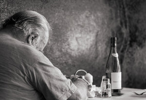 Monochrome photograph of elderly man dining alone