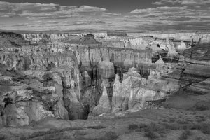 Black and white Arizona canyon landscape with layered cliffs and a cloud lined horizon.