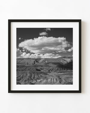Broad white clouds above rugged Arizona desert ridges in black and white.