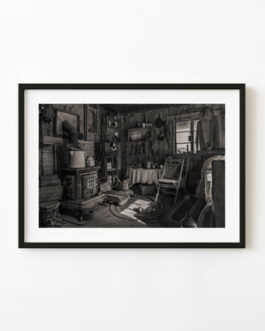 Window light falls across a wood stove and furnishings inside an old Arizona miner’s cabin.