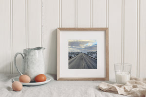 A winter road through Arizona with pale surface streaks and snow on low shrubs.