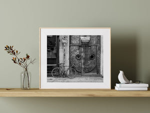A parked bicycle contrasts with the intricate metal surface of an Art Deco door.