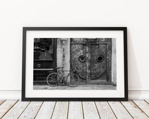 Art Deco door and bicycle with brickwork and layered street textures in black and white.