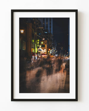 Blurred pedestrians move beneath restaurant lights on an Asakusa street at night in Tokyo.
