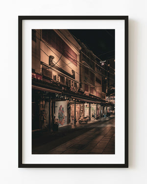 Warm shop lights illuminate a quiet Asakusa street beneath the dark Tokyo night sky.