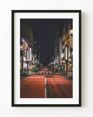 A red road leads between illuminated shops beneath the dark night sky in Asakusa, Tokyo.