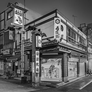 Painted shutters wrap around a traditional Asakusa restaurant beneath windows and railings.