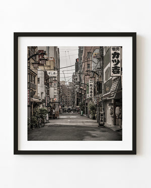 Lanterns, shop signs and overhead wires line a narrow Asakusa street in muted colour.