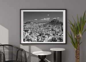 A broad monochrome view of Athens links dense city buildings with distant hills.
