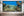 Panoramic underwater Bahamas scene with silver fish, branching reef edges and blue ocean water.