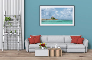 Colour coastal photograph of a thatched shoreline shelter beside clear Bahamas water.