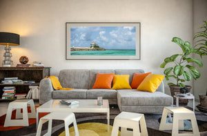 Panoramic Bahamas seascape with a thatched shelter, rocky shore and bright turquoise water.
