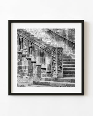 Carved stone posts and diagonal rails border worn Barcelona steps in black and white.