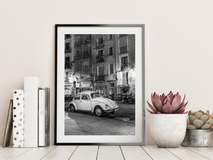 Black and white Barcelona night photograph of a parked Volkswagen Beetle beneath old apartment facades.