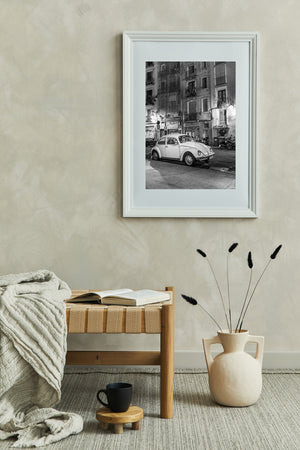 Tall Barcelona buildings rise above a parked Beetle and a quiet strip of night pavement.