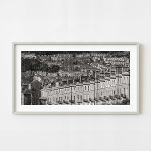Framed black and white print of a cityscape with buildings on a white wall