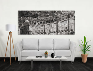 Salón con sofá blanco, mesa de café y un gran cuadro de paisaje urbano en blanco y negro en la pared.