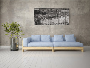 Sofá azul claro contra una pared gris con un cuadro de paisaje urbano en blanco y negro.