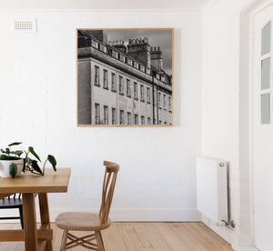 Projecting dormers interrupt the roof slope above orderly rows of narrow window panes.